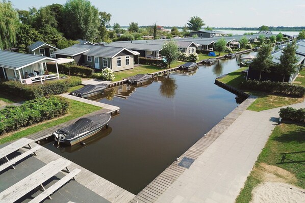 A canal-side residential area with houses, a dock, and a boat. - Nice chalet with ac and sloop (Giethoorn)