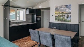 Une cuisine de taille réduite comprenant un coin repas, un banc et un tableau représentant un paysage.