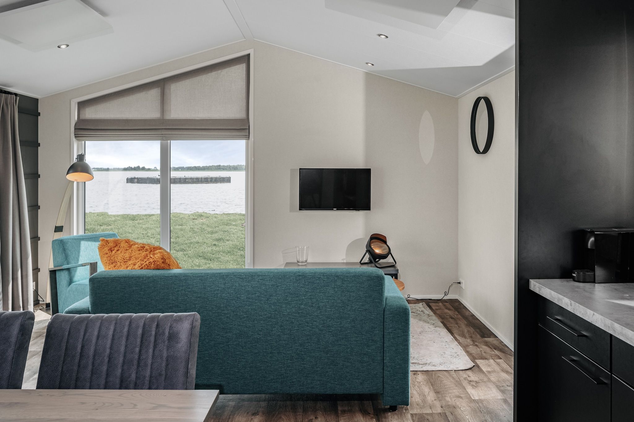 A modern living room with a sofa, a coffee table, a TV, and a view of a body of water.
