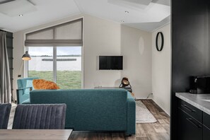 Una sala de estar moderna con un sofá, una mesa de centro, un televisor y vistas a una masa de agua.