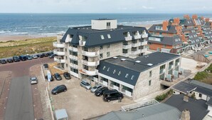 A multi-story hotel with a stone facade, balconies, and a view of the beach.