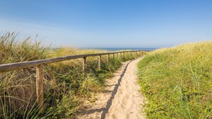 A sandy path bordered by wooden railings, leading towards a distant horizon.
