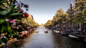 A canal with boats, lined with trees and buildings on both sides.