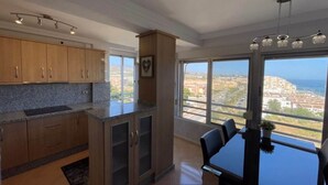 Cocina moderna con encimeras de granito, gabinetes de madera y un comedor con vistas a la ciudad y al océano.