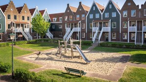 A playground with slides and a bench, surrounded by traditional houses with steep roofs. - Cozy Volendam Getaway (Volendam)