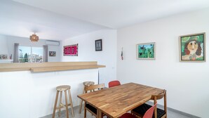 A modern dining area with a wooden table and chairs, a bar counter, and artwork on the walls.