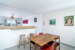 Un comedor moderno con una mesa y sillas de madera, una barra y obras de arte en las paredes.