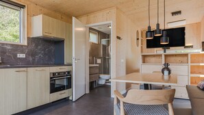 Et moderne køkken med træskabe, en indbygget ovn og et spiseområde med et bord og stole.