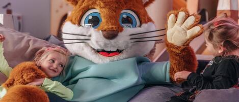 A person in a large rabbit costume sitting on a couch with a child.