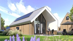 A modern building with a sloped roof, large windows, and a patio area with outdoor seating.