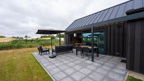 Un espace extérieur aménagé avec une table et des chaises, un banc et un parasol.