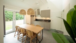 Une cuisine moderne avec un coin repas, de grandes fenêtres et une vue sur la verdure.