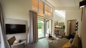 Un salon moderne avec un téléviseur à écran plat, un canapé, un fauteuil et une table basse.