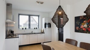 A modern kitchen with white cabinets, a black countertop, and a wooden dining table with four chairs.