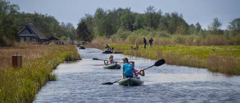 A narrow waterway with people paddling kayaks.
