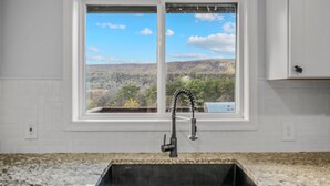 A kitchen with a window offering a view of a mountainous landscape. - Black Bear Cabin - Fire pit - grill- view- pets-fireplace-king bed-wifi-gameroom (Berkeley Springs)