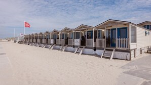 A row of beachside mobile homes with a flag and a sign indicating amenities.