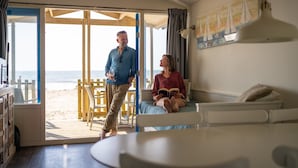 A room with a bed, a table, and a view of the beach through an open door. - Beach House in Wijk aan Zee with Sea View (Wijk aan Zee)
