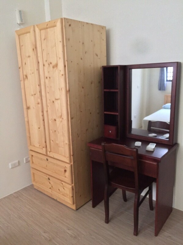 A wooden wardrobe with multiple compartments and a mirror cabinet with a bed visible in the reflection. - Guiyuehome (Huxi)