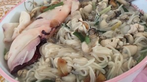 Een kom noedelsoep met kip en champignons.