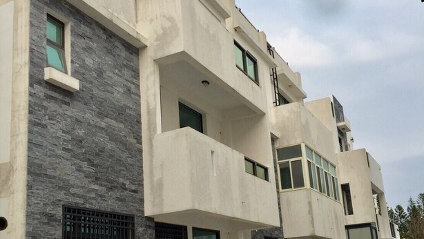 Een modern meerlaags woongebouw met balkons, grote ramen en een gevel van zowel steen als beton.