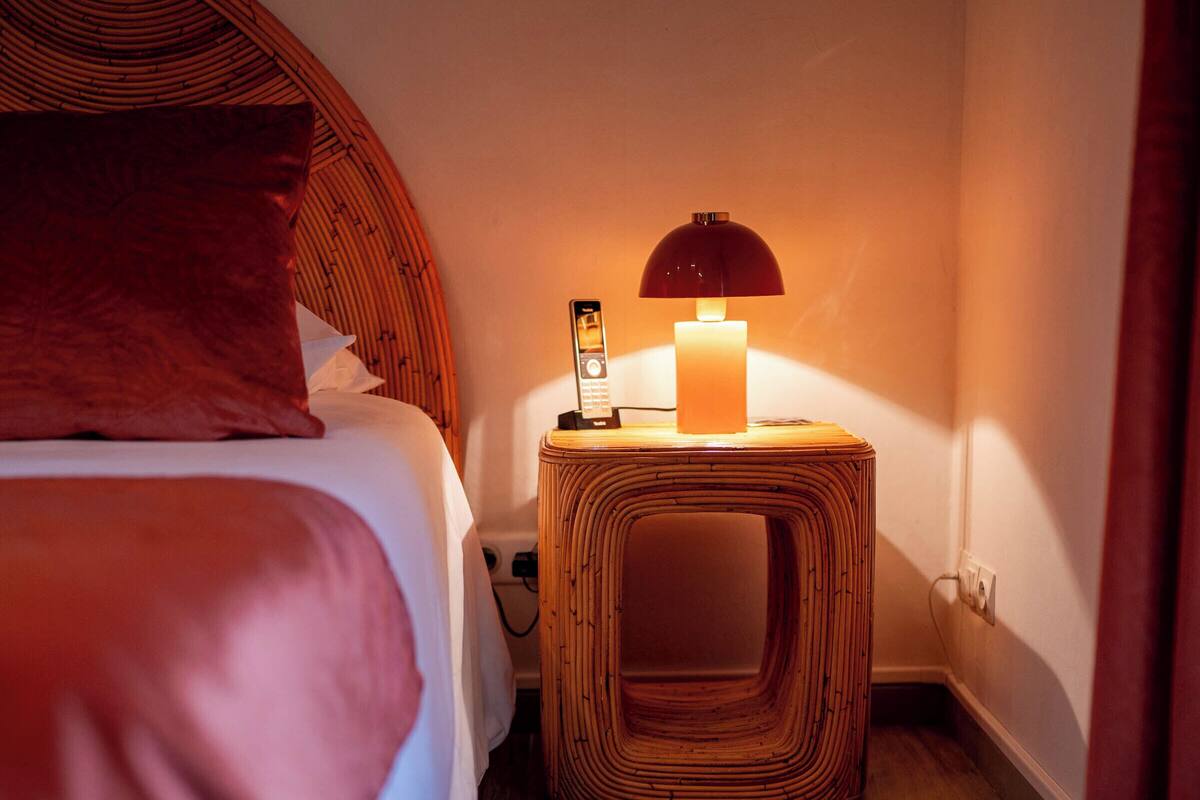 Une chambre à coucher avec un lit, une table de chevet avec une lampe et un plancher en bois.