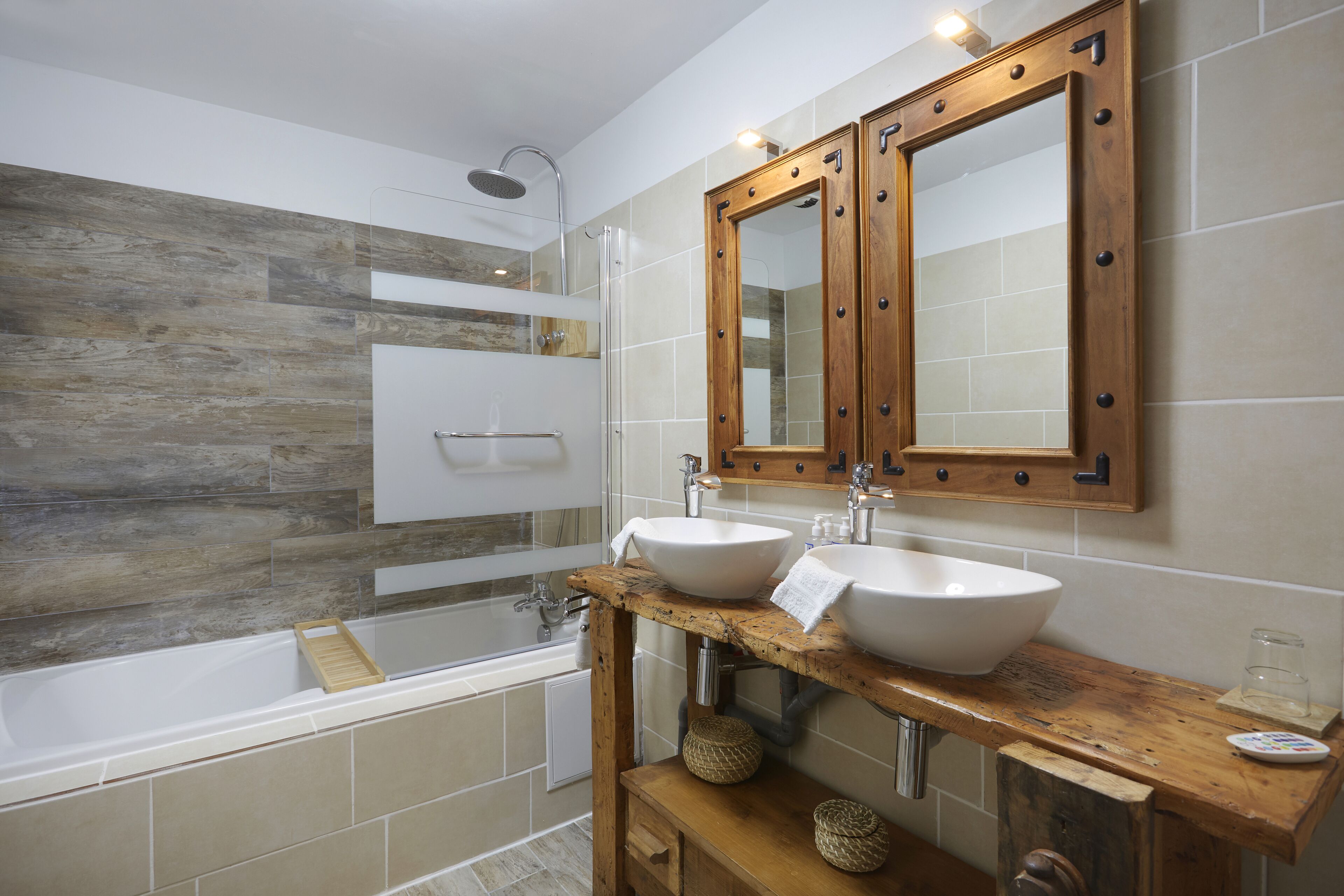 A modern bathroom with a wooden vanity, two sinks, a shower, and a large mirror.
