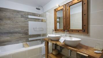 A modern bathroom with a wooden vanity, two sinks, a shower, and a large mirror.