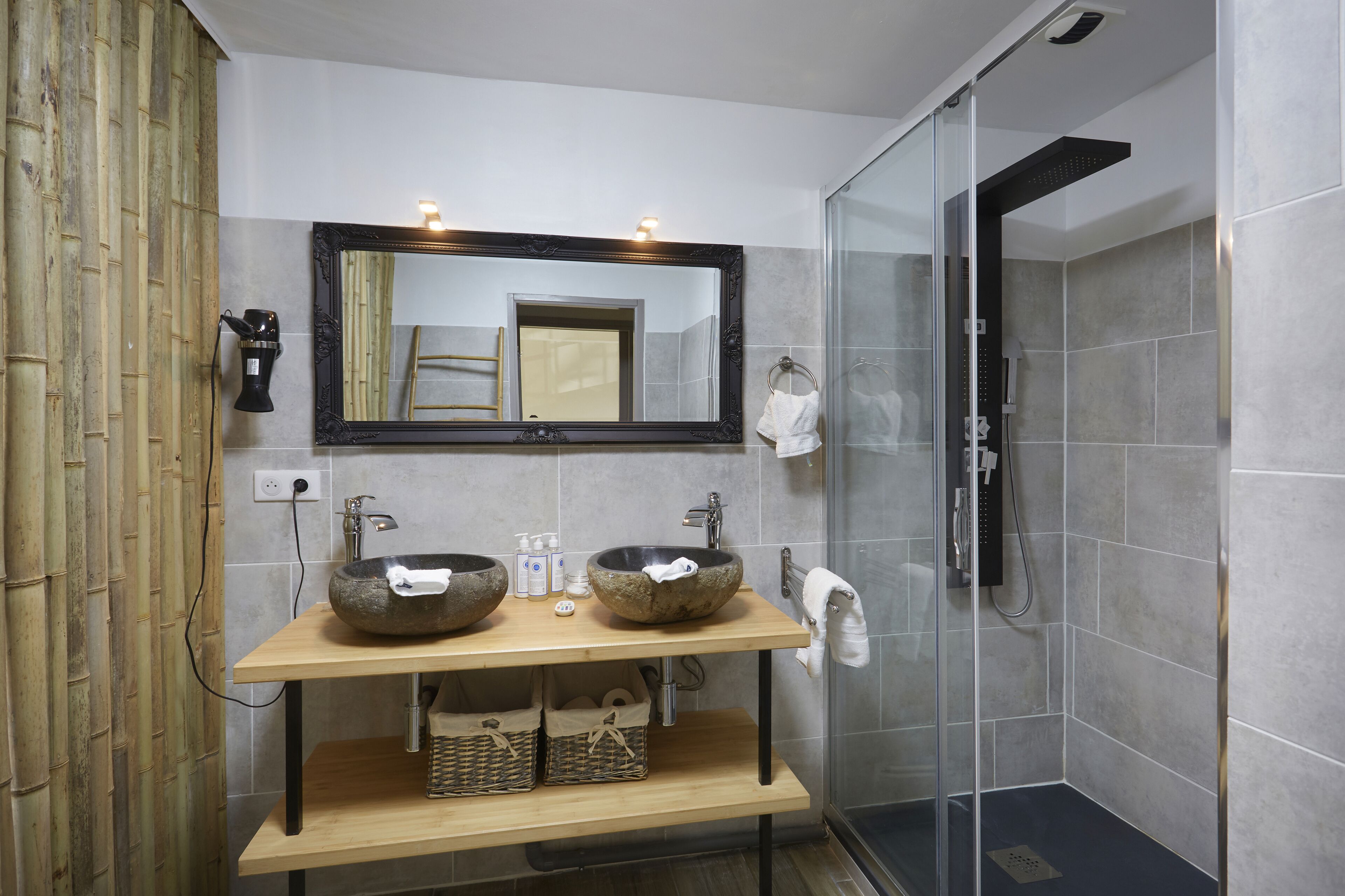 A bathroom with two stone sinks, a mirror, and a glass shower enclosure.