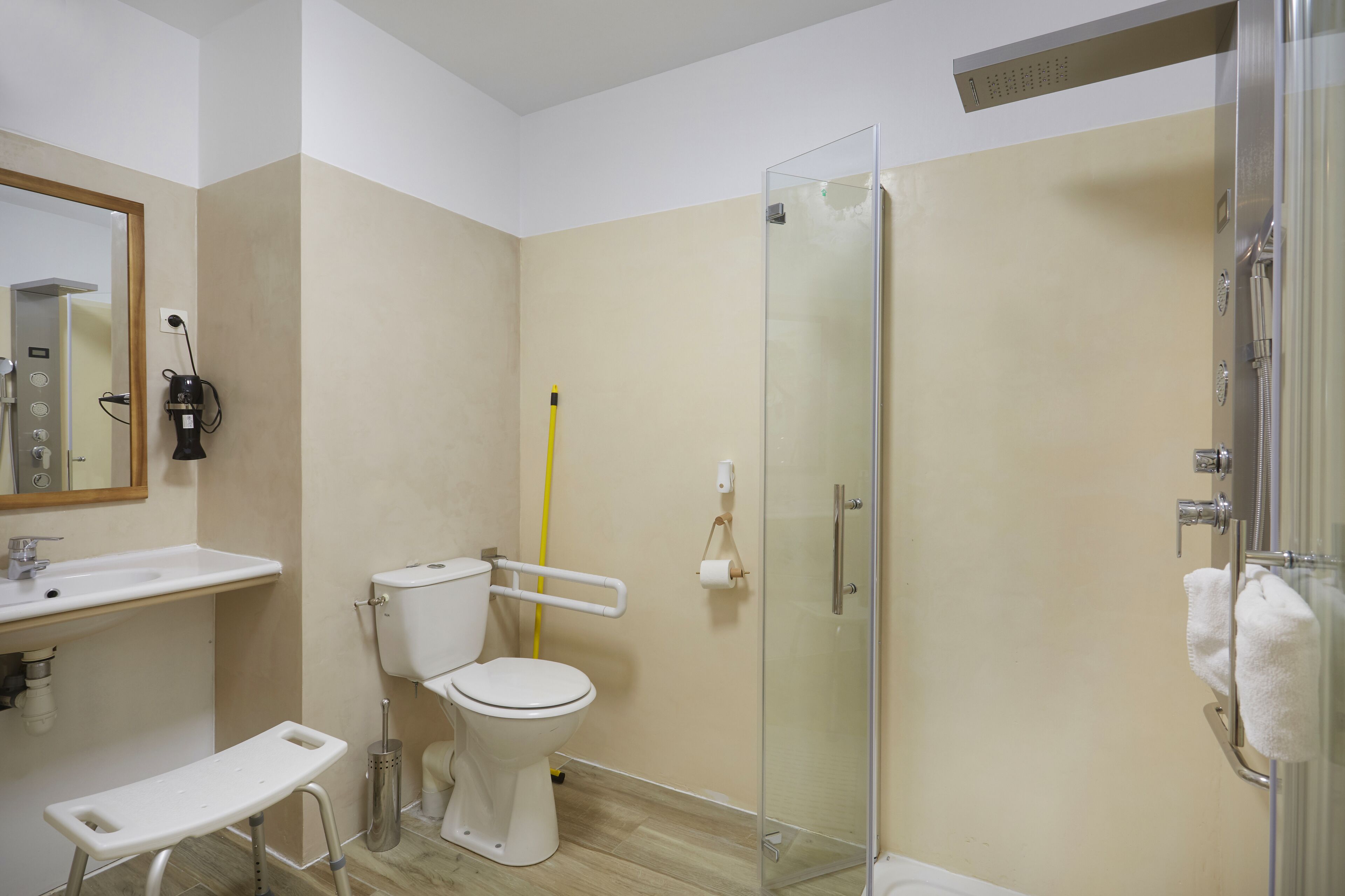 Um banheiro moderno com box de vidro, vaso sanitário branco, pia e espelho.
