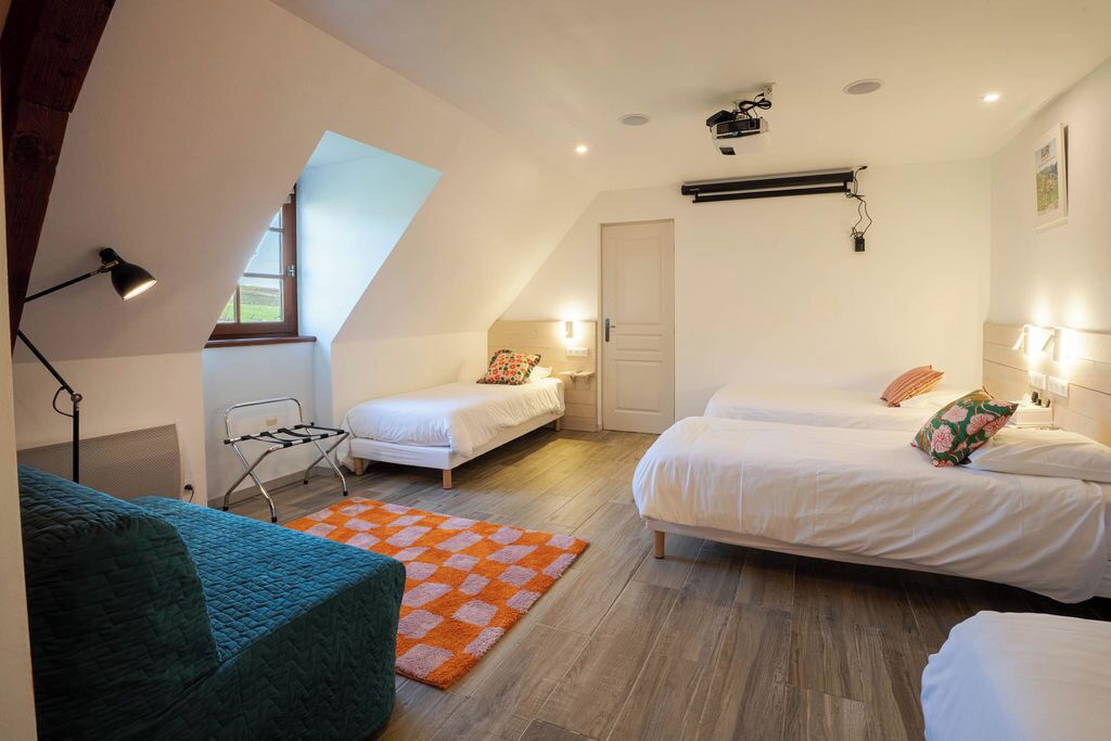 A bedroom with two single beds, a sofa, a standing lamp, a ceiling fan, and a window.