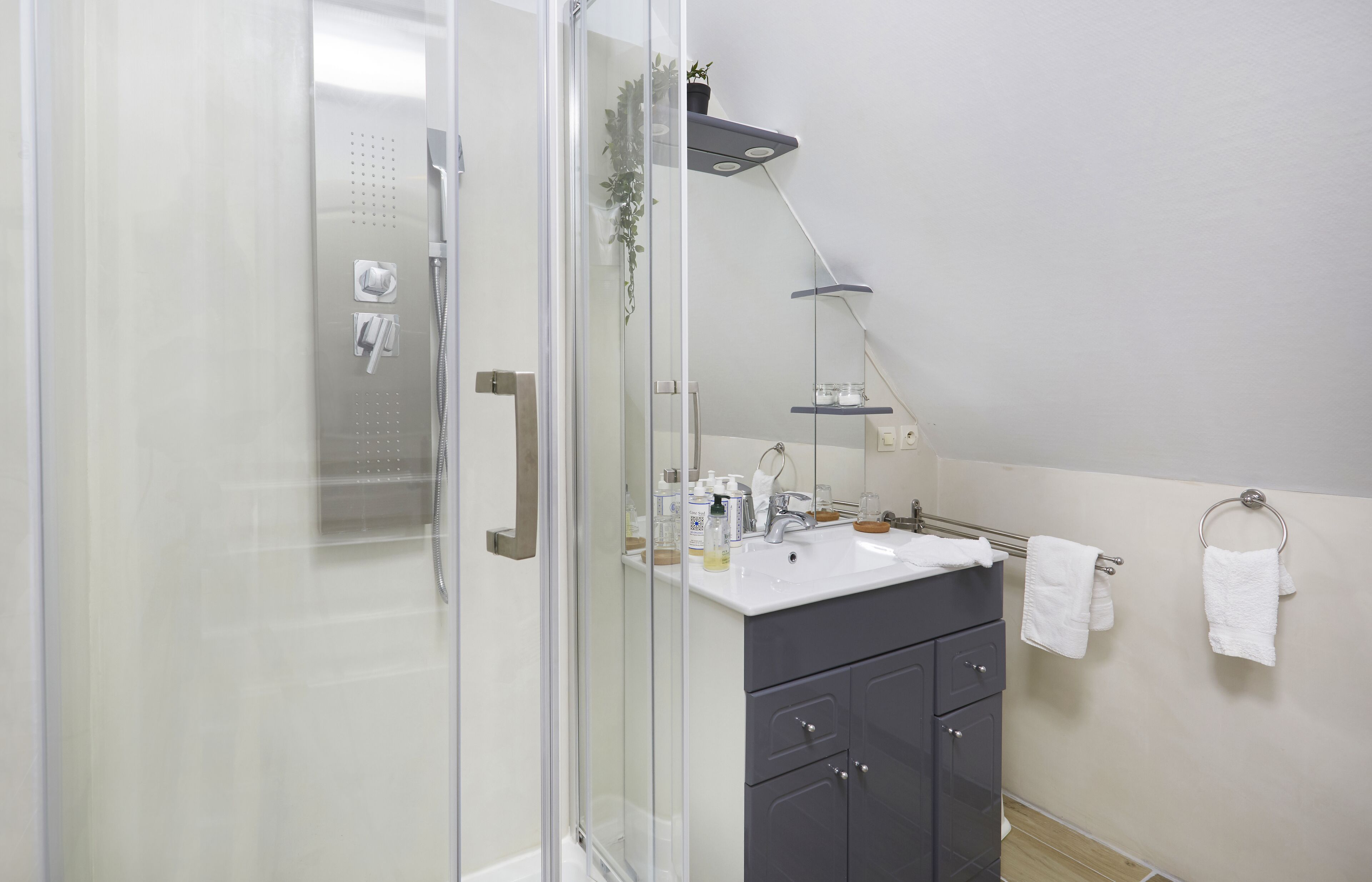A modern bathroom with a glass shower enclosure, a vanity with a sink, and a towel rack.