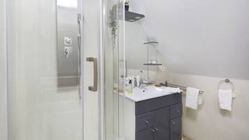 Moderni kylpyhuone, jossa on lasinen suihkuseinä, allaskaappi ja pyyhekoukku.