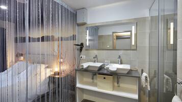 Ein modernes Badezimmer mit zwei Waschbecken, einer Duschkabine aus Glas und einem großen Spiegel.