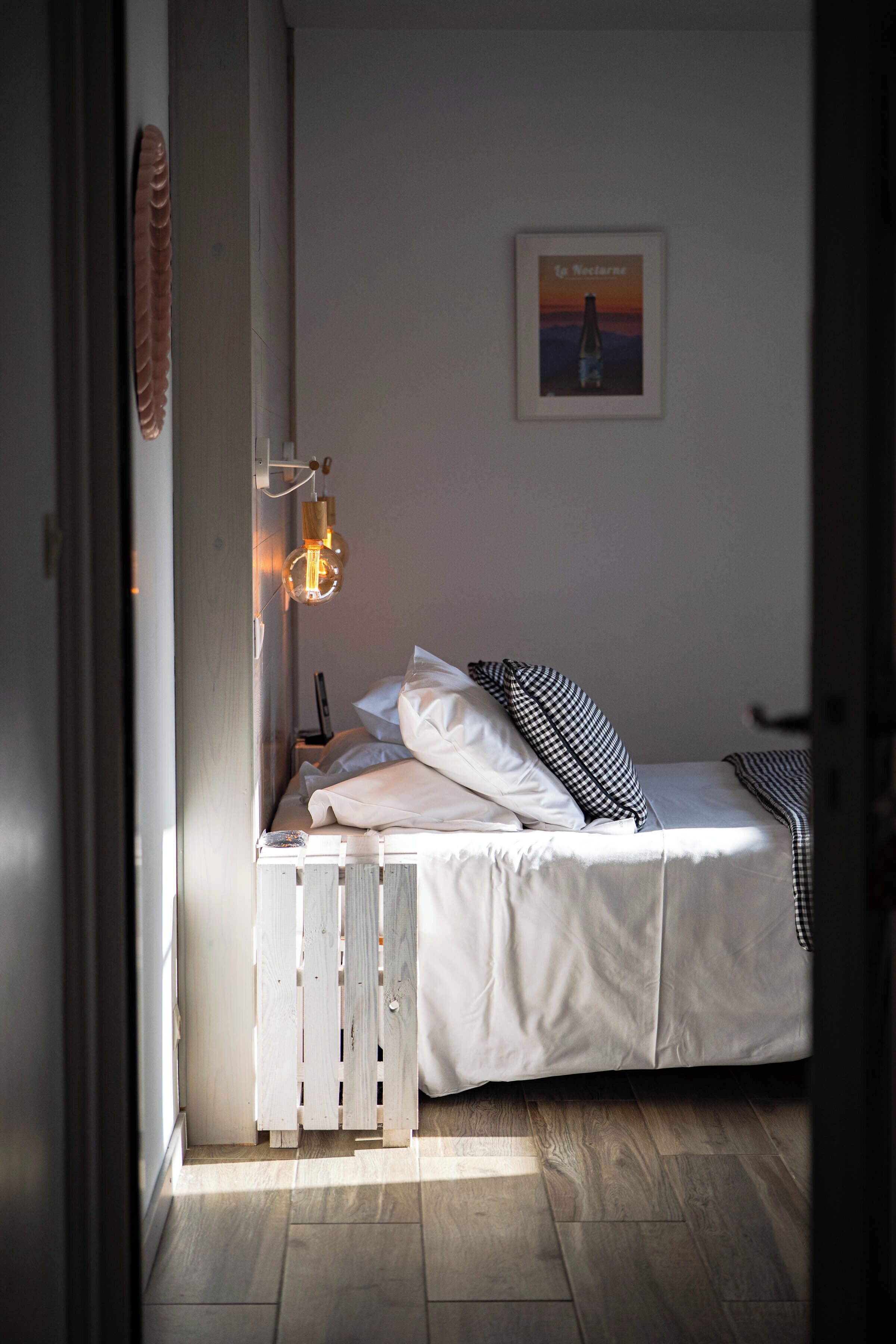 A bedroom with a bed, a wall-mounted light, and a framed picture.