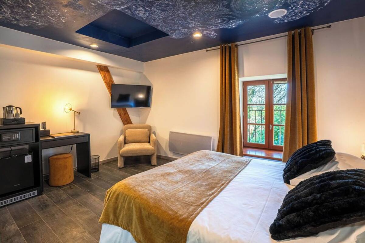 Une chambre d’hôtel moderne équipée d’un lit, d’un bureau, d’une chaise, d’une télévision et d’une fenêtre avec des rideaux.