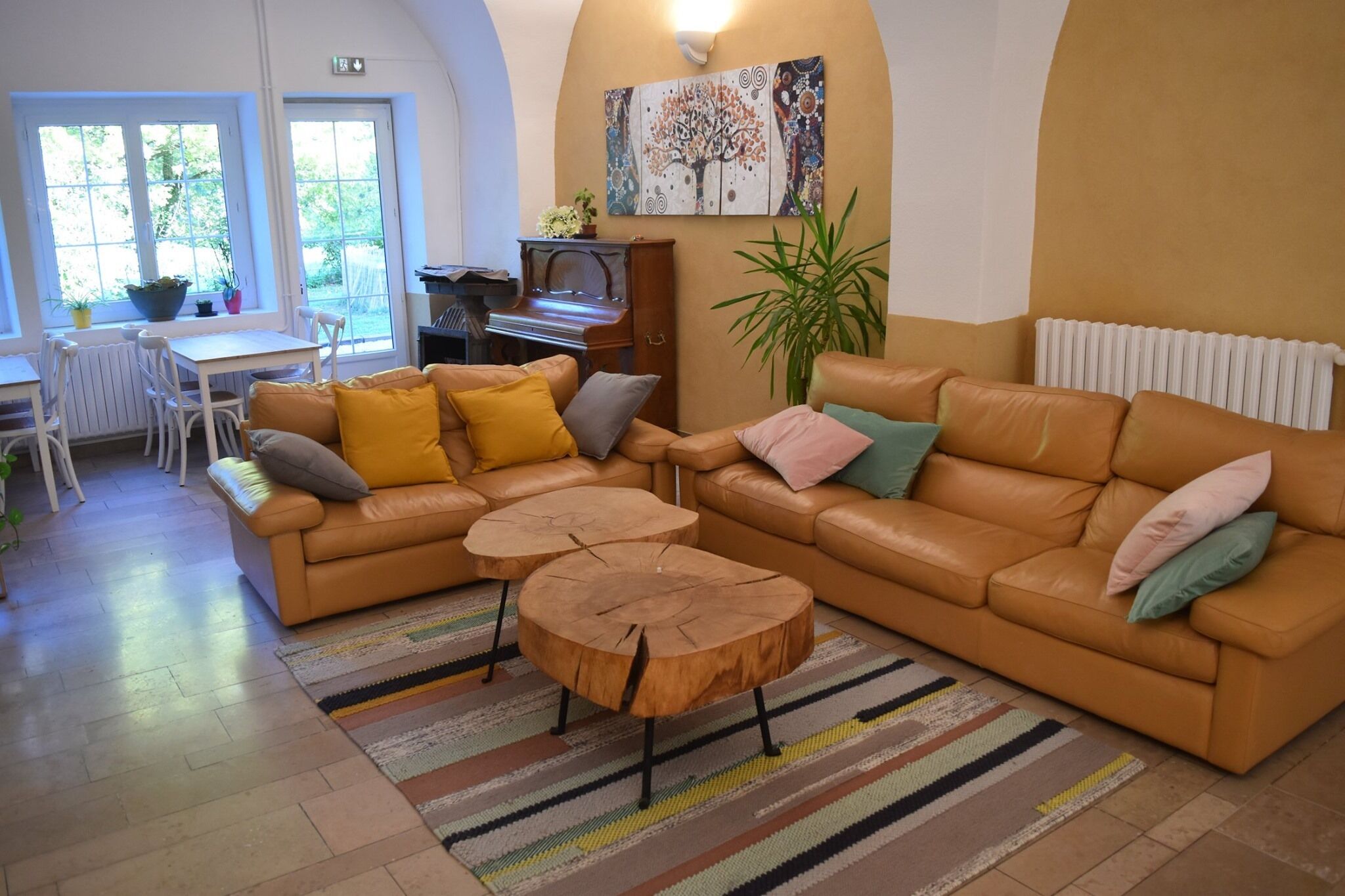 A living room with a sofa, two coffee tables, a piano, and a painting on the wall.