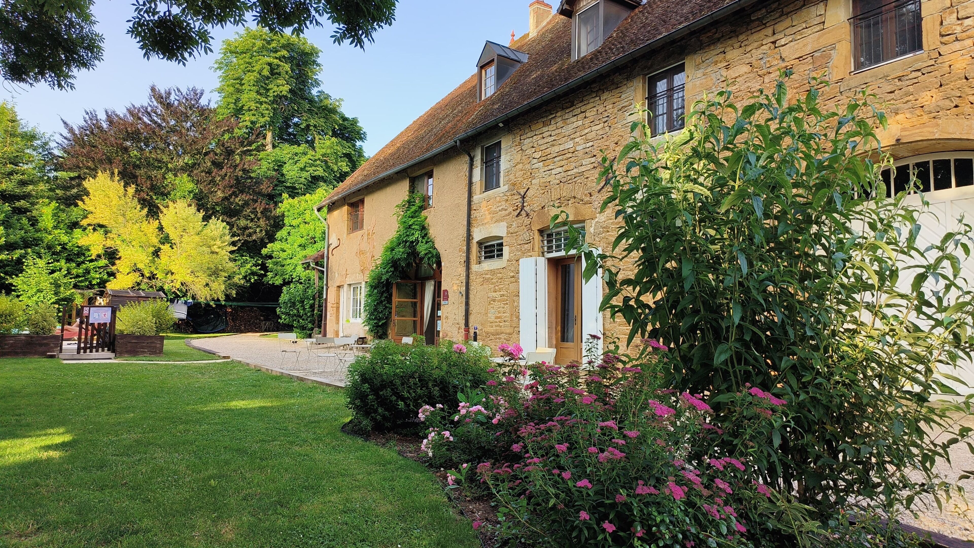 A stone building with a garden, a small outdoor seating area, and a pathway leading to the entrance.
