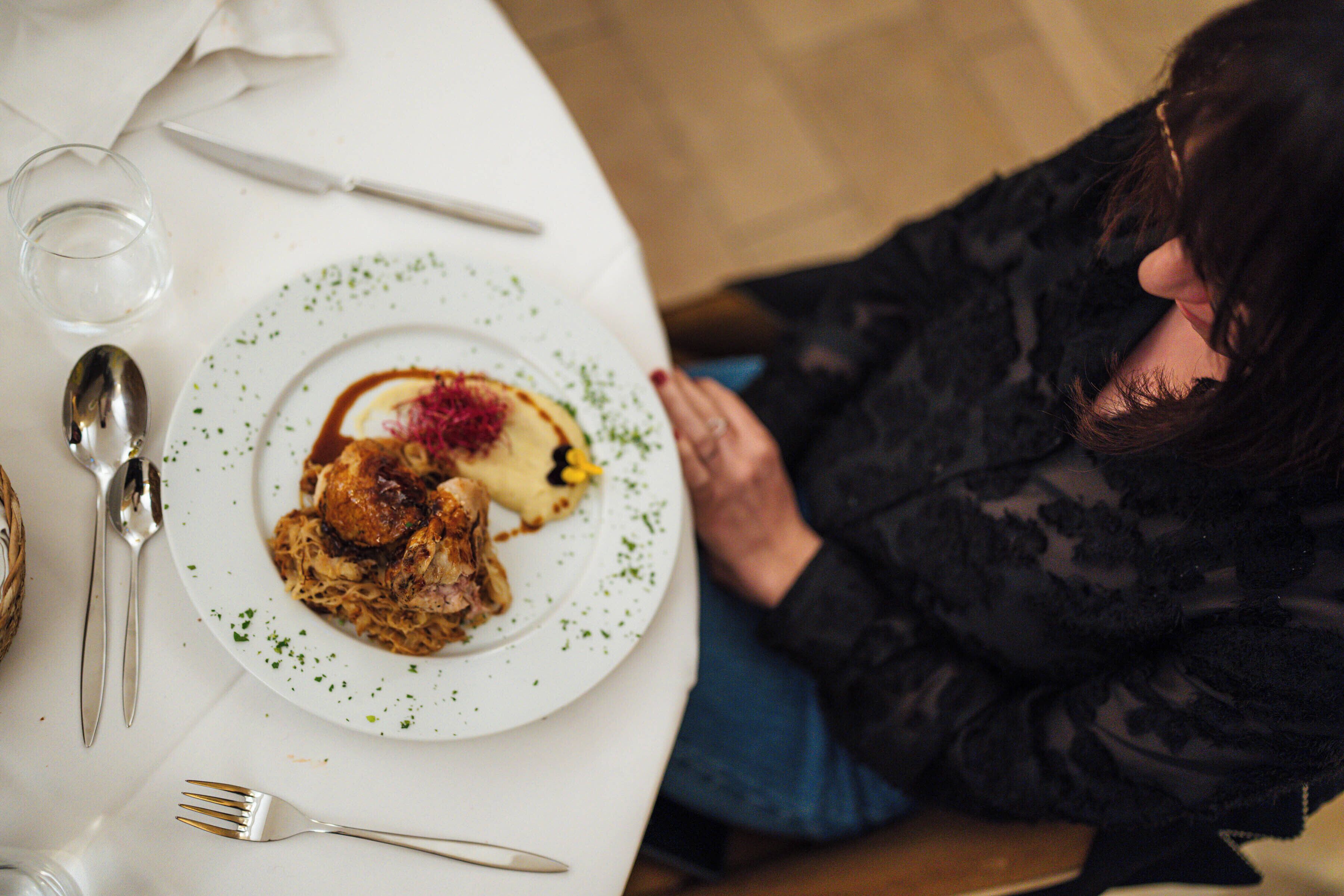 Uma mesa de jantar com um prato de comida, talheres e um copo de água.