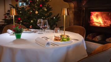 A dining table set for two with a Christmas tree in the background.
