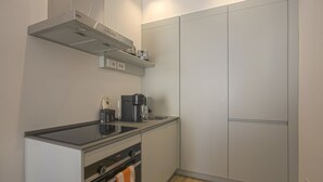 Une cuisine compacte équipée d’un four encastré, d’une machine à café et d’un grille-pain posés sur le plan de travail.