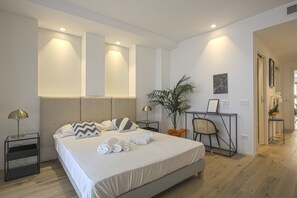 A modern hotel room with a large bed, bedside tables, a desk, and a potted plant. - Milan Chic Suite 6 (Milan)