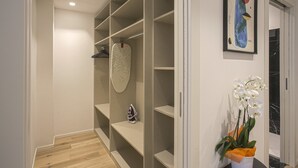 Un couloir avec un plancher en bois, une porte blanche, un mur blanc et un tableau abstrait encadré.