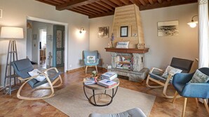 Una sala de estar acogedora con vigas de madera, una chimenea de piedra y asientos cómodos.
