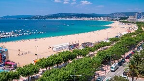A coastal cityscape with a wide beach, a marina with boats, and a clear blue sky. - Stylish Apartment in Palamós - Near Sea with Parking (Palamós)