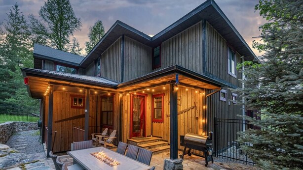 A two-story wooden cabin with a covered patio area featuring outdoor seating and a fire feature. - Private chalet on golf course 5 min to Silver mntn (Kellogg)