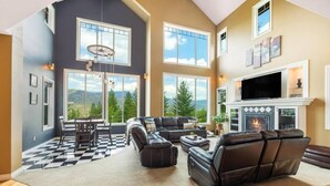 A spacious living room with a fireplace, large windows, and a checkered floor. - Private chalet on golf course 5 min to Silver mntn (Kellogg)