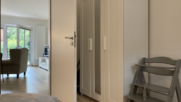 Un dormitorio con cama, armario y escritorio con silla.