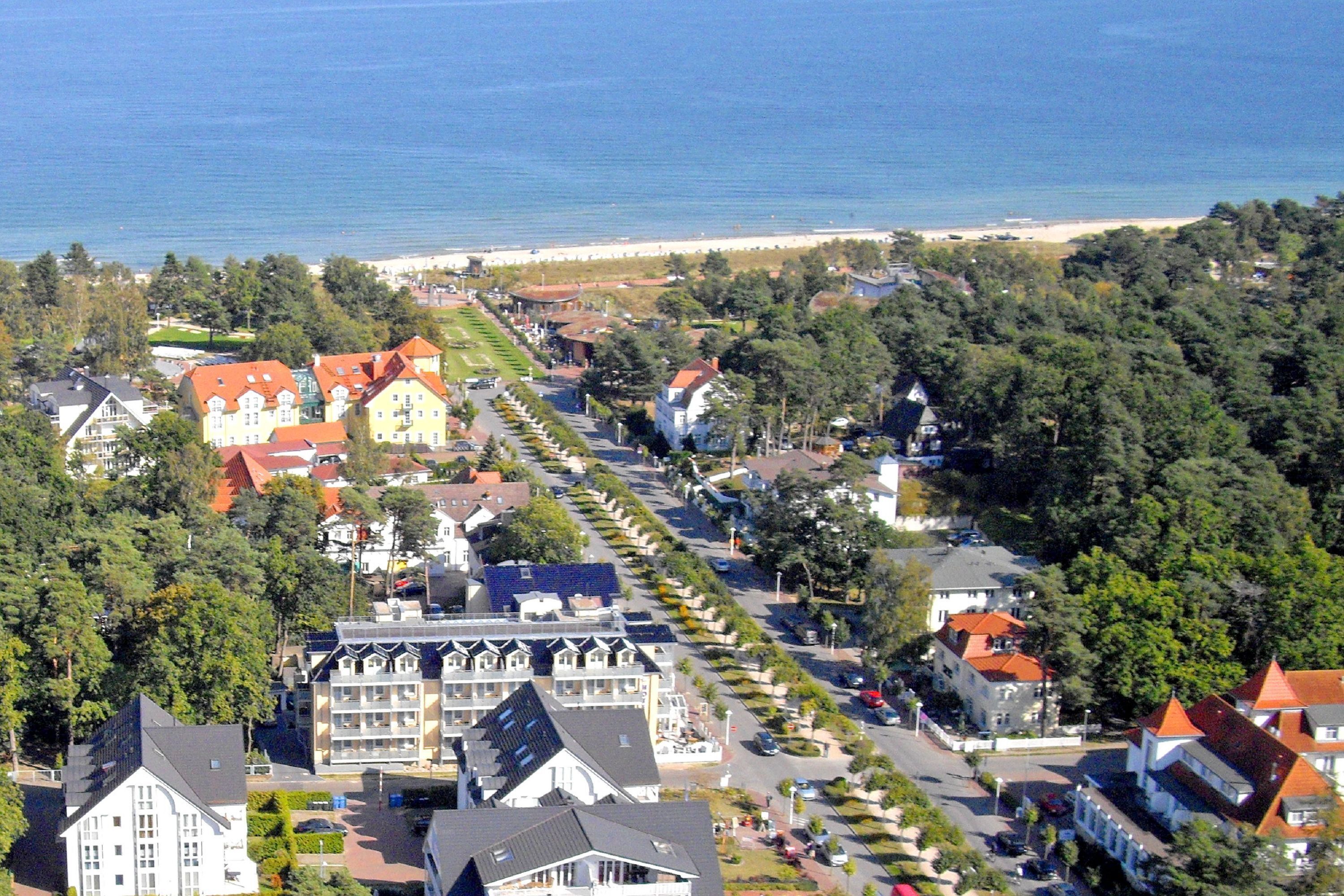 Une ville côtière dont la rue principale est bordée d’immeubles, avec une plage en arrière-plan, et où se côtoient des bâtiments résidentiels et commerciaux.
