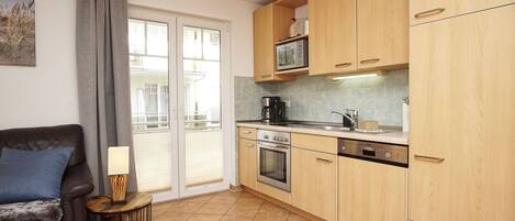 A compact kitchen with wooden cabinets, a built-in oven, and a microwave.